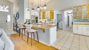 Een ruime keuken met een centraal eiland, houten kastjes en hanglampen.