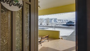A view from inside a building looking out to a snowy landscape with a bench and a 'welcome' sign. - Beautiful Historic Home Near Bryce Canyon! (Cannonville)