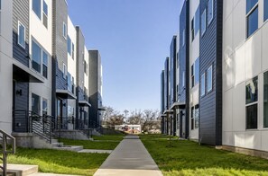 A modern residential building with a central pathway, flat roofs, and uniform windows.