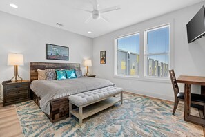 A bedroom with a bed, bedside tables, a bench, a desk, and a TV.