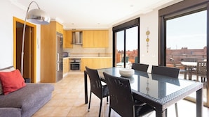 A modern apartment with a dining area, kitchen, and a balcony with a city view.