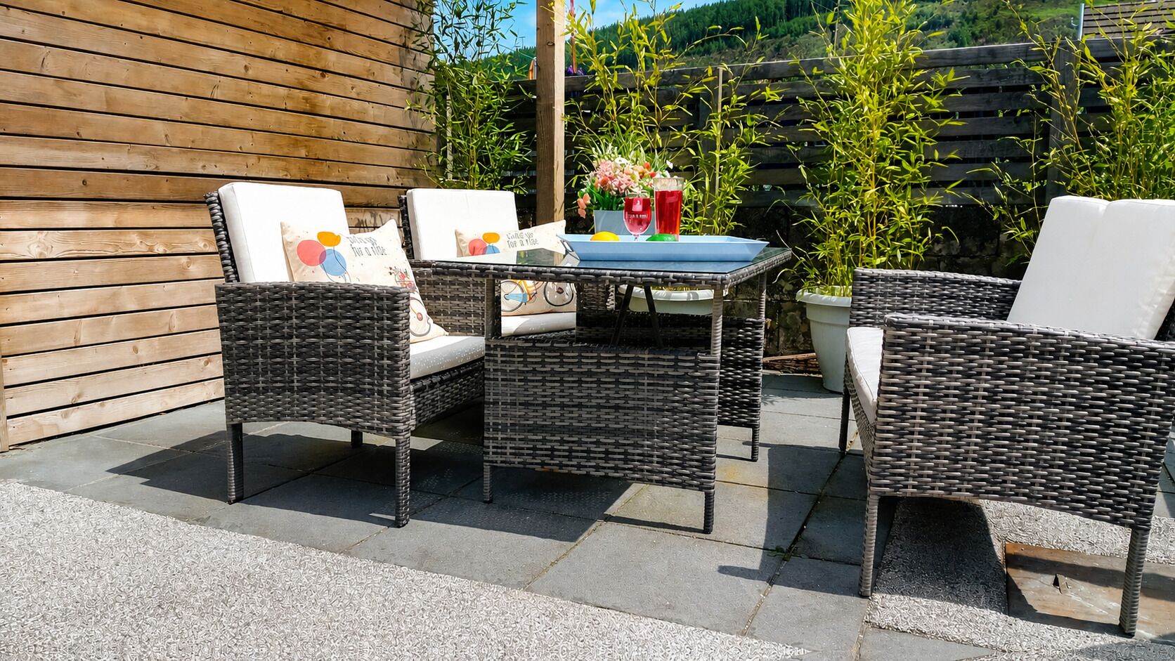 An outdoor patio with wicker furniture, a table, and a potted plant.