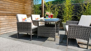 Een terras buiten met rieten meubilair, een tafel en een bloempot.