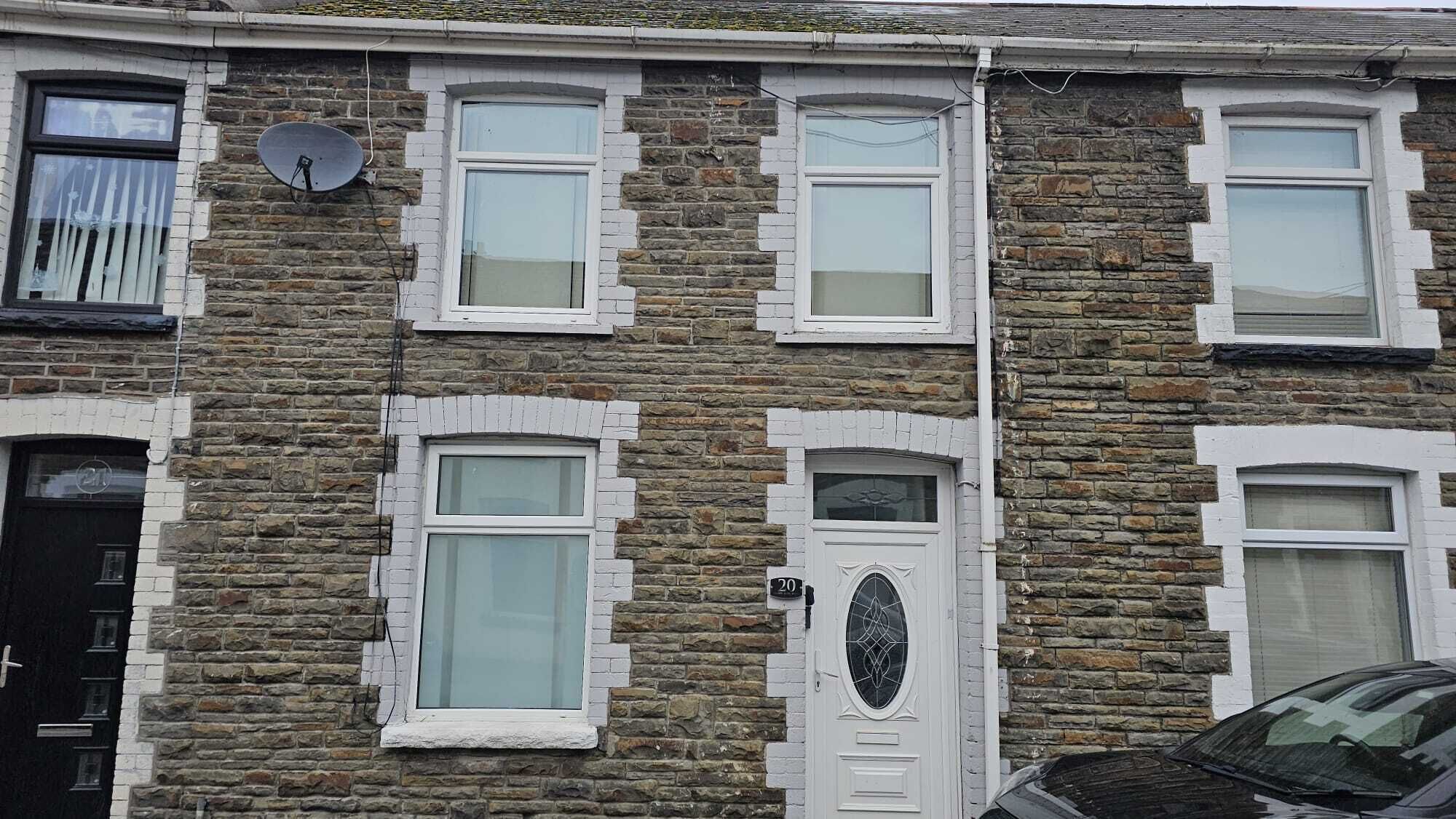 A two-story stone house with white-framed windows and a door with a glass panel.