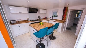 Een moderne keuken met witte kastjes, een houten kookeiland en blauwe barkrukken.