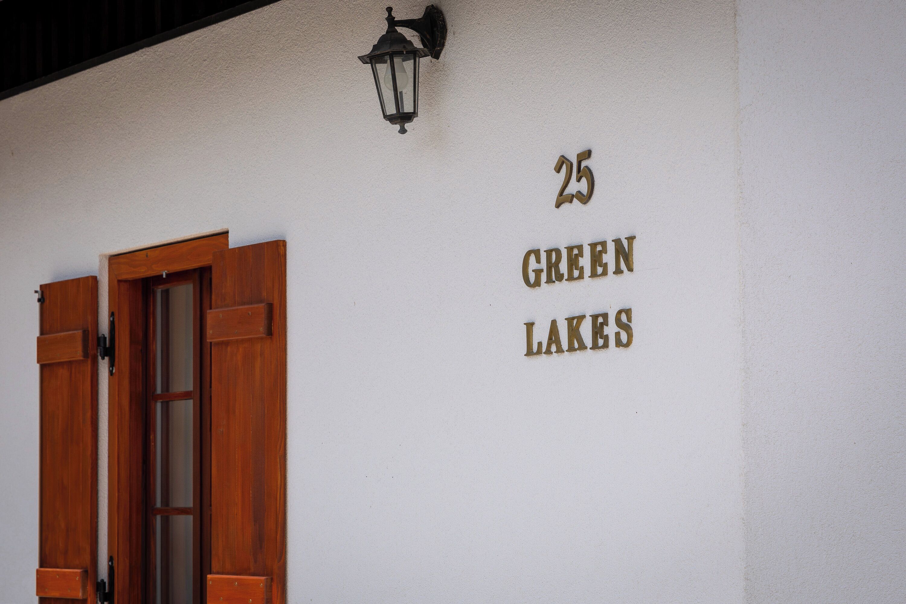 A building with a wooden door and a sign reading "25 GREEN LAKES".