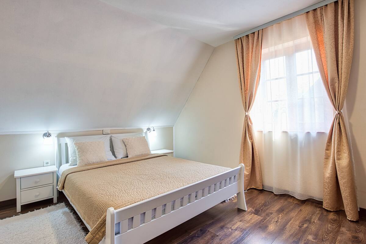 A bedroom with a single bed, a nightstand, and a window with curtains.
