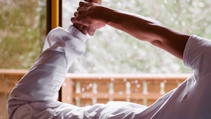 A person performing a yoga pose in a room with a large window and a wooden railing. - Berg- & Erlebnis-Resort MarktlAlm - Chalets & Lodges (Stadl-Predlitz)