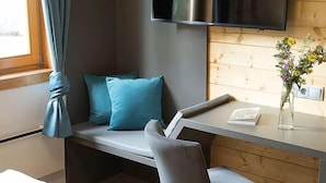 A modern hotel room with a bed, a desk, a chair, a TV, and a window with curtains. - Berg- & Erlebnis-Resort MarktlAlm - Chalets & Lodges (Stadl-Predlitz)