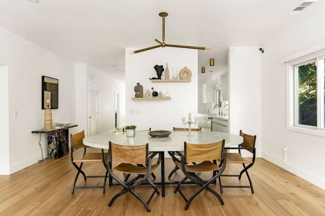 Un comedor moderno con una mesa redonda, seis sillas y una lámpara colgante.