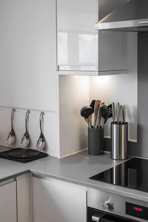 A modern kitchen with stainless steel appliances, a black induction cooktop, and a digital clock displaying 10:29.