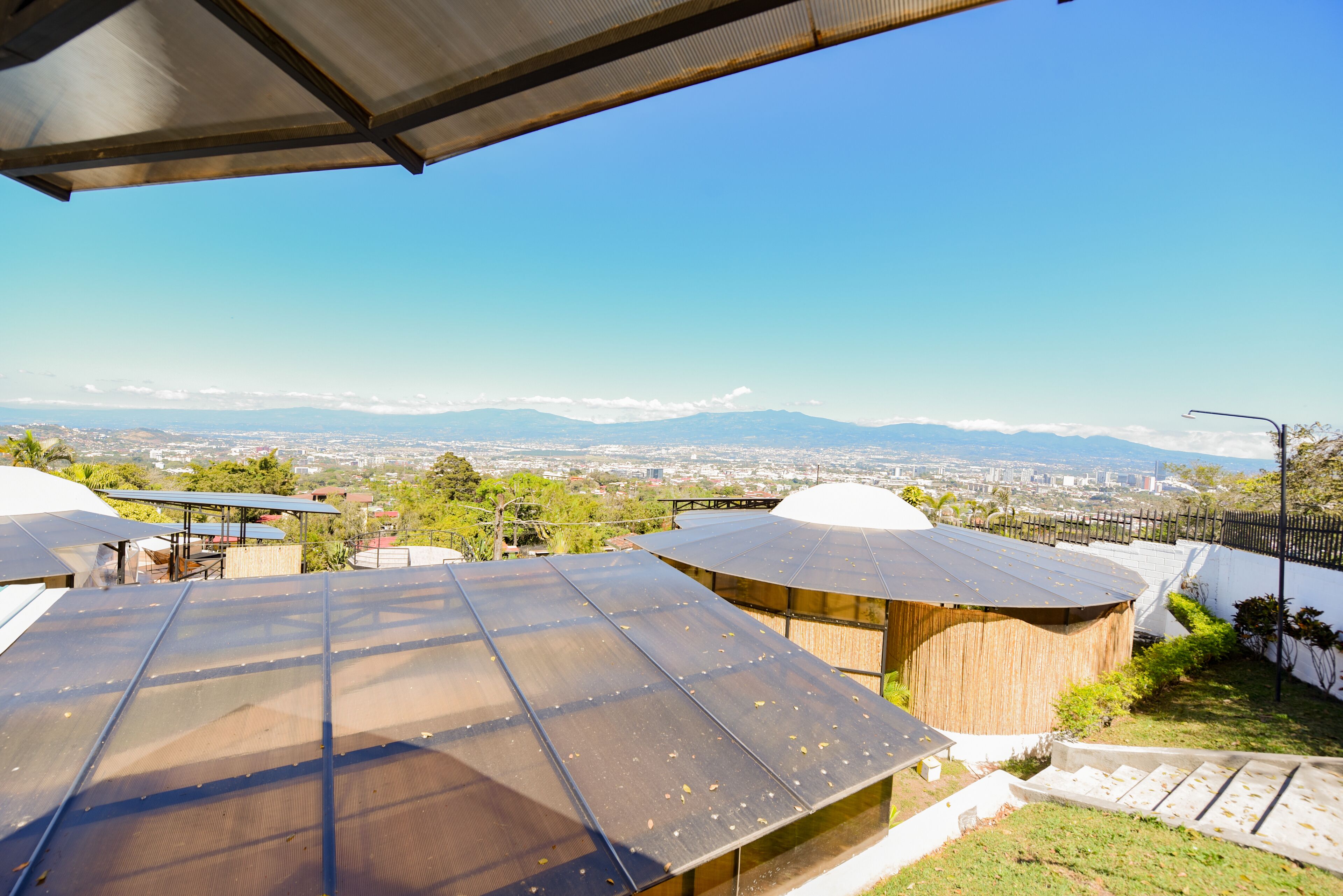 Un tetto con pannelli solari, una zona relax coperta e vista su montagne lontane e sullo skyline urbano.