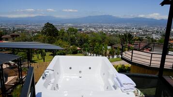 Un bain à remous avec vue sur la ville, entouré de verdure et doté d’une terrasse en bois.