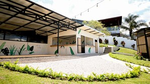 A building with a covered entrance, a mural with plant illustrations, and a staircase leading to a second level. - ALMA Glamping  (San Antonio)