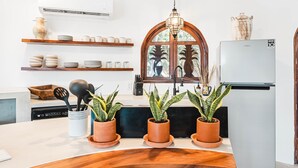 Una cocina moderna con un refrigerador blanco, estantes de madera y plantas en macetas.