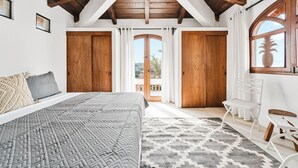 Un dormitorio con una cama grande, puertas de madera, un balcón y vistas al exterior.