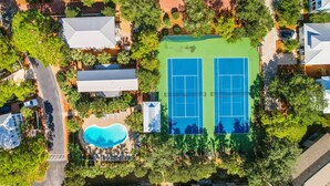 Vue aérienne d’un quartier résidentiel avec un court de tennis, une piscine et les maisons environnantes.