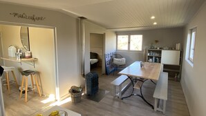 A spacious living area with a high ceiling, a dining table, a sofa, and a kitchen area with a counter and stools. - The family cabin (Champdieu)