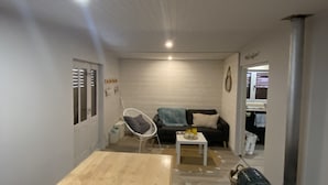 A modern living room with a wooden table, a white chair, a sofa, and a small coffee table. - The family cabin (Champdieu)