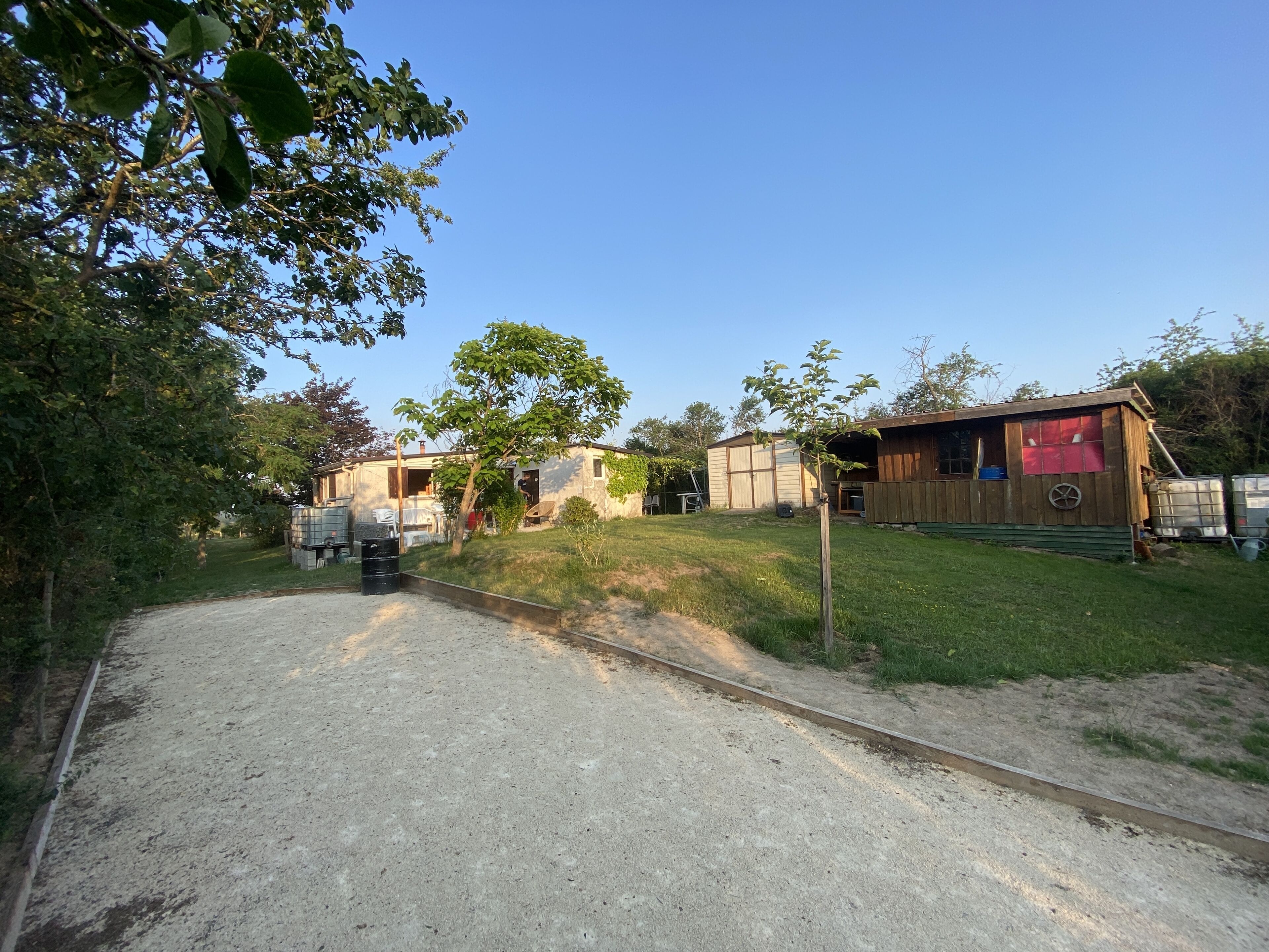 Una propiedad rural con camino de grava, un cobertizo de madera y una casa pequeña.