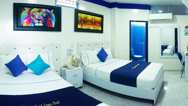A hotel room with two beds, a desk, and a mirror. - Hotel Luna Azul  (Florencia)