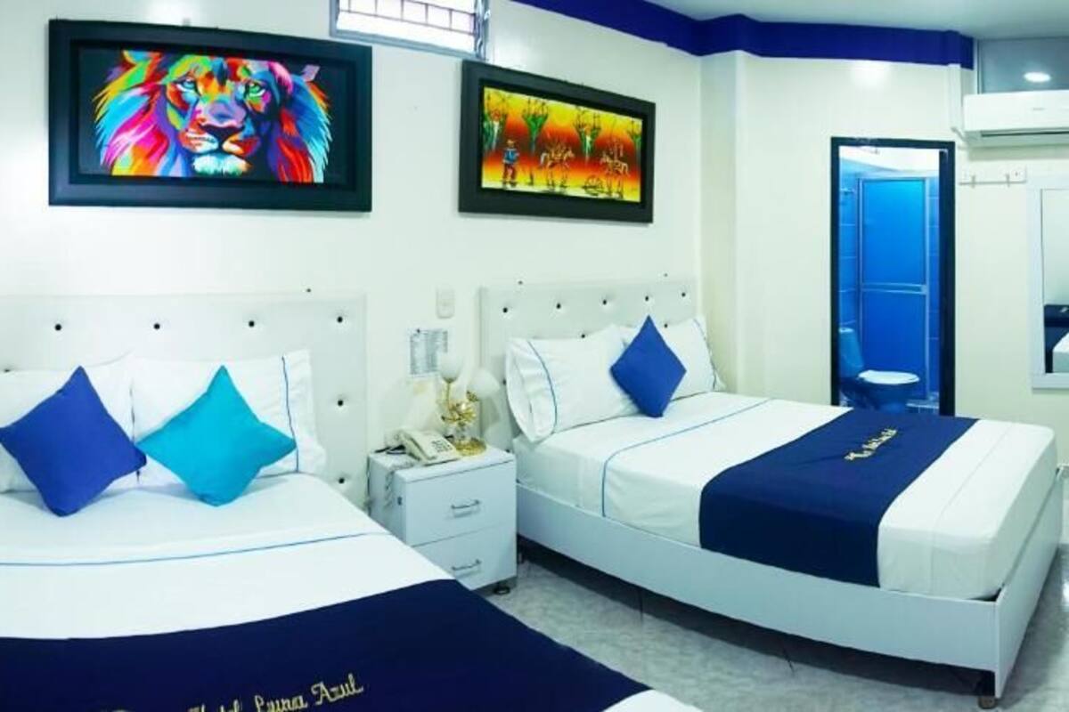 A hotel room with two beds, a desk, and a mirror.