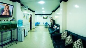 A reception area with a reception desk, a fish tank, a television, and a waiting area with a couch and chairs. - Hotel Luna Azul  (Florencia)