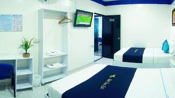 Habitación de hotel con cama, escritorio, silla, televisor y puerta.