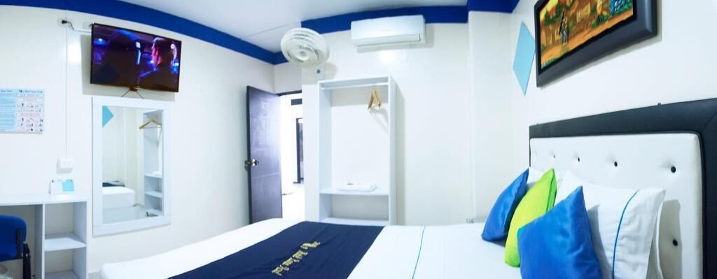 Une chambre d’hôtel avec un lit, une télévision, une armoire et un bureau.