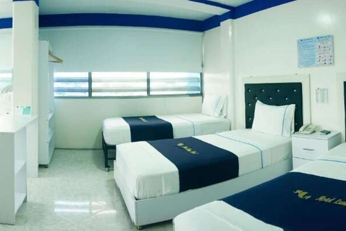 A hotel room with two beds, a desk, and a chair.