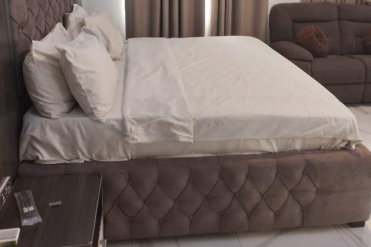 A modern bedroom with a large bed, a sofa, and a TV.