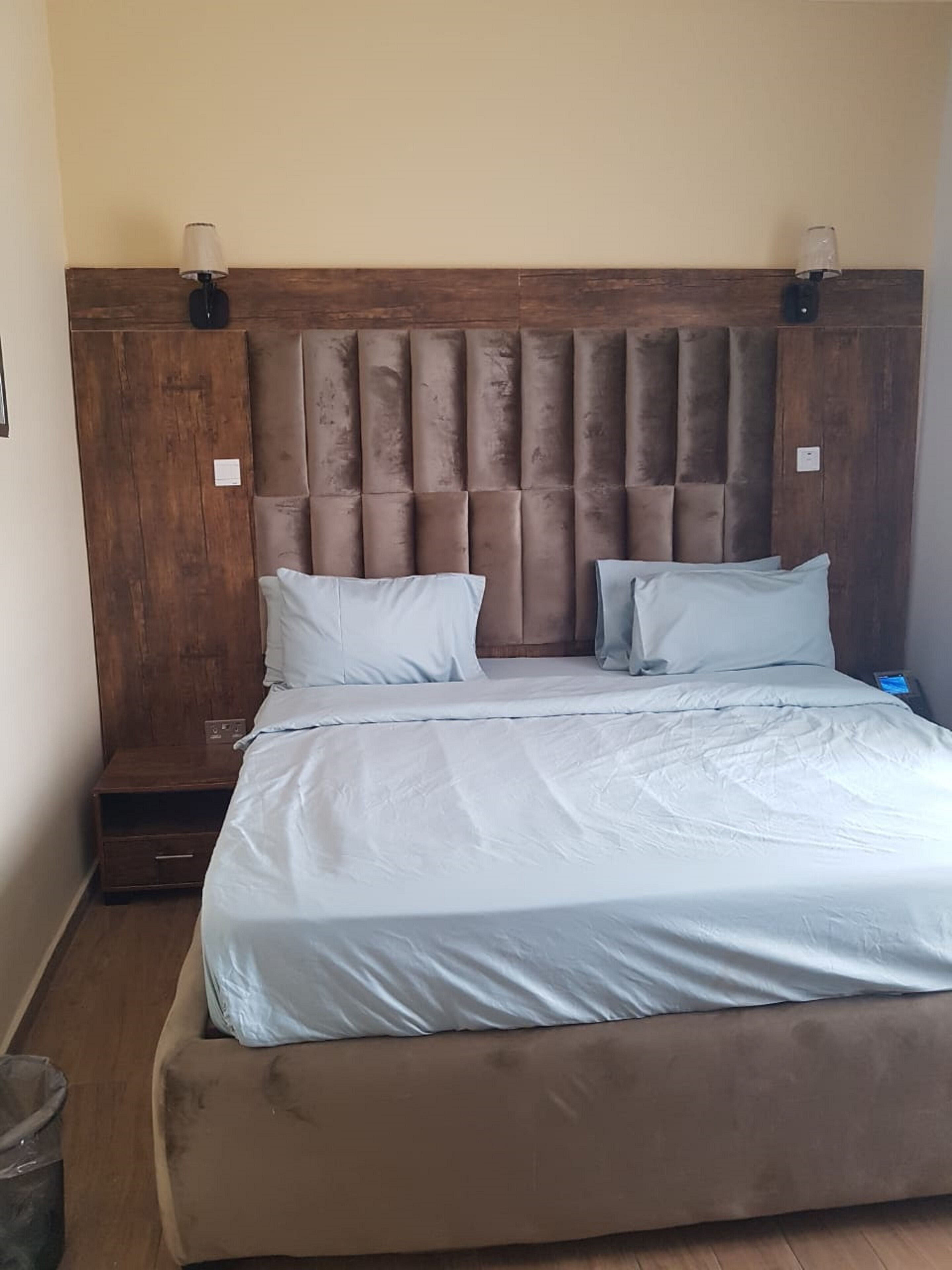 A bedroom with a large bed, a wooden headboard, and a nightstand.