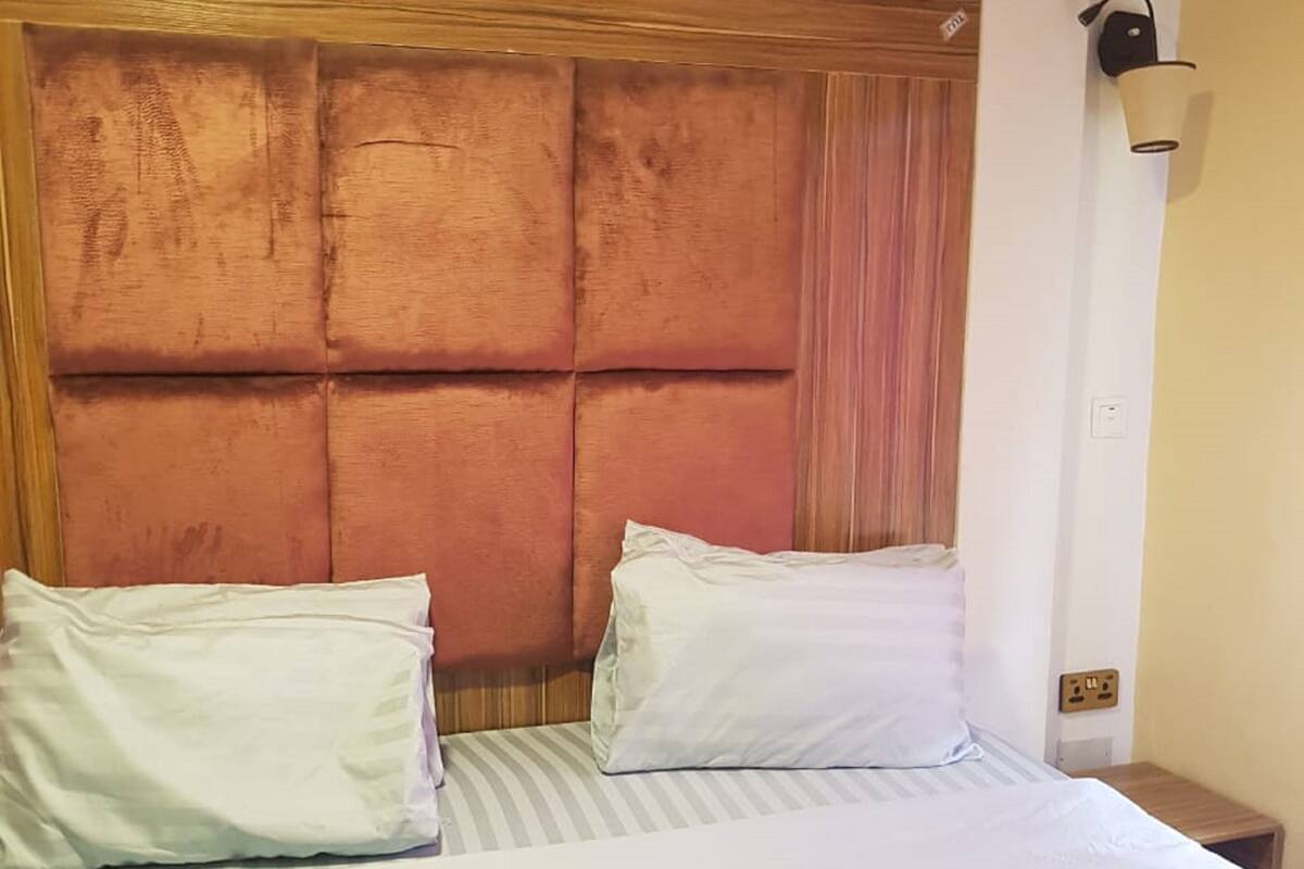A hotel room with a large bed, a wooden headboard, and a nightstand with a lamp.