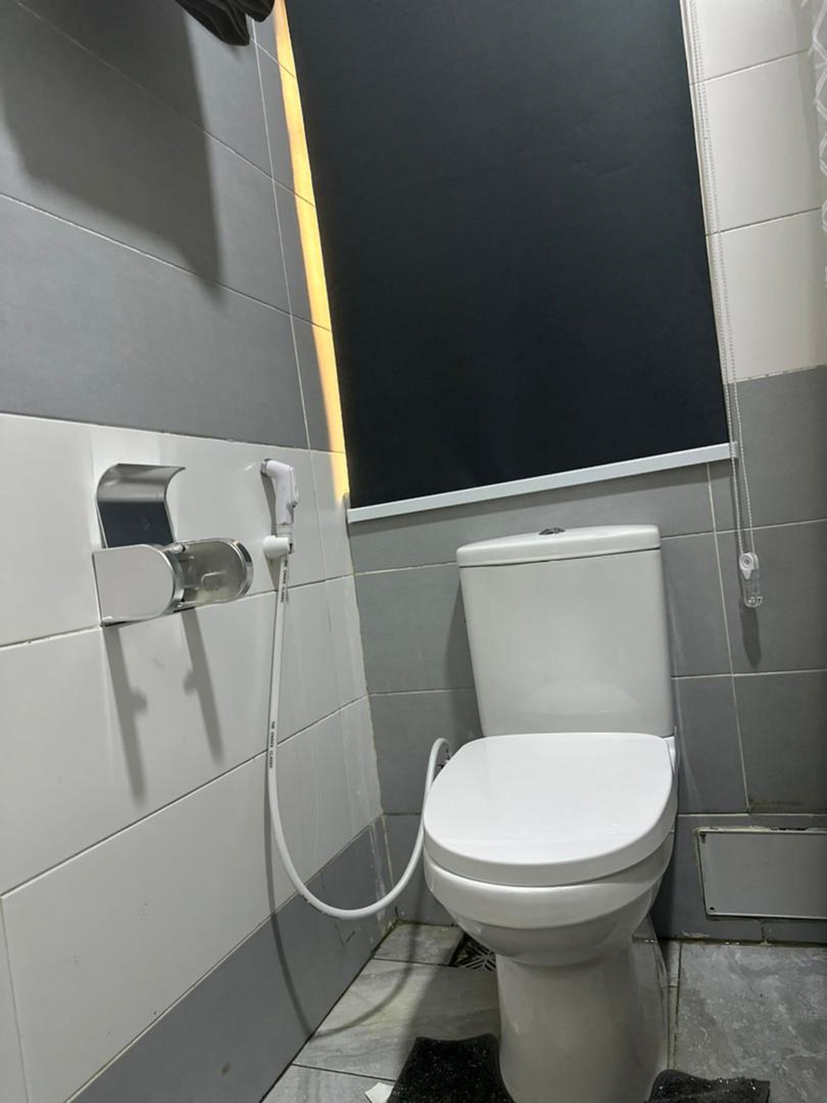 A small, modern bathroom with a toilet, a hand dryer, and a paper towel dispenser.