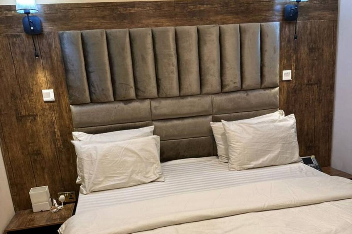 A bedroom with a wooden headboard, two bedside tables, and a bed with white bedding.
