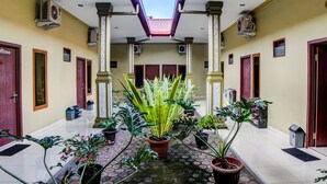 A corridor with potted plants, doors, and air conditioning units. - OYO 92430 Anora Homestay (Medan)