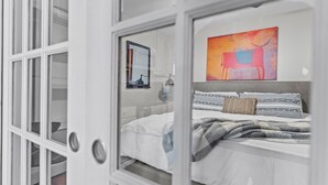 A bedroom with a bed, a window, and a painting on the wall. - Cozy Convenient downtown Condo (Wilmington)