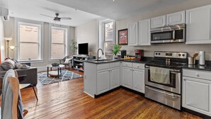 A modern kitchen with white cabinets, stainless steel appliances, and hardwood flooring. - Cozy Convenient downtown Condo (Wilmington)