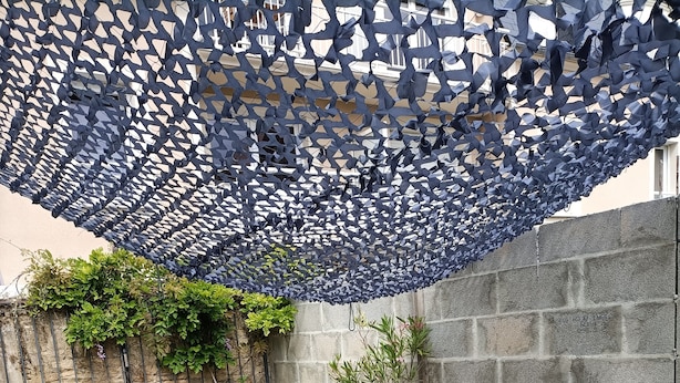 A wooden deck with a table and chairs, a blue decorative canopy, and a potted plant. - Pretty little house, in a quiet private courtyard 5 minutes from the sea (Luc-sur-Mer)