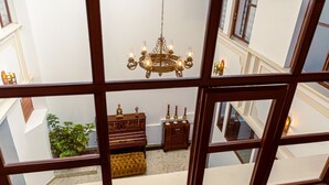 A room with a chandelier, a piano, a small table, and a plant. - Catedral Internacional (Quito)