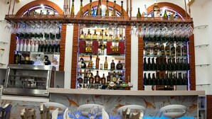 A bar area with shelves of liquor bottles, a wine cooler, and hanging glasses. - Catedral Internacional (Quito)