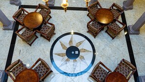A lobby with a central circular floor design, surrounded by tables and chairs. - Catedral Internacional (Quito)