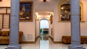 A hallway with marble flooring, two sofas, and a view through an archway. - Catedral Internacional (Quito)