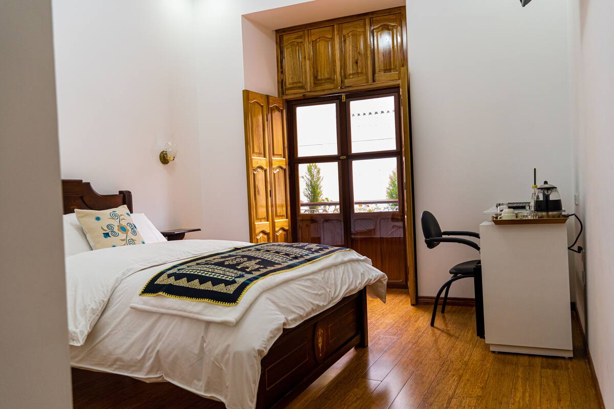 Un dormitorio con cama de madera, un escritorio y una ventana con vistas.