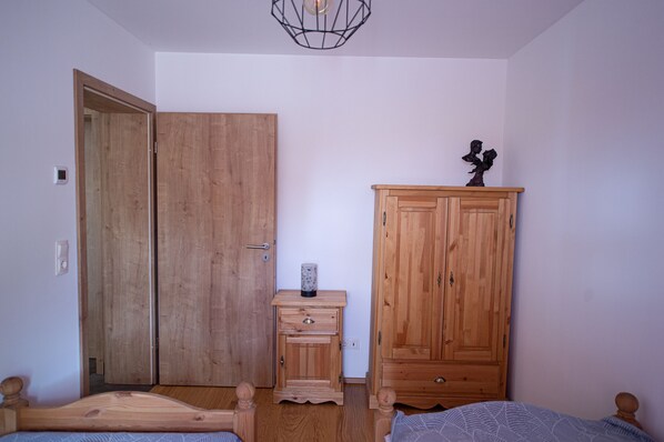 A bedroom with a wooden wardrobe, a bedside table with a lamp, and a bed. - "Blütenzauber" Apartment (Büttelkow)