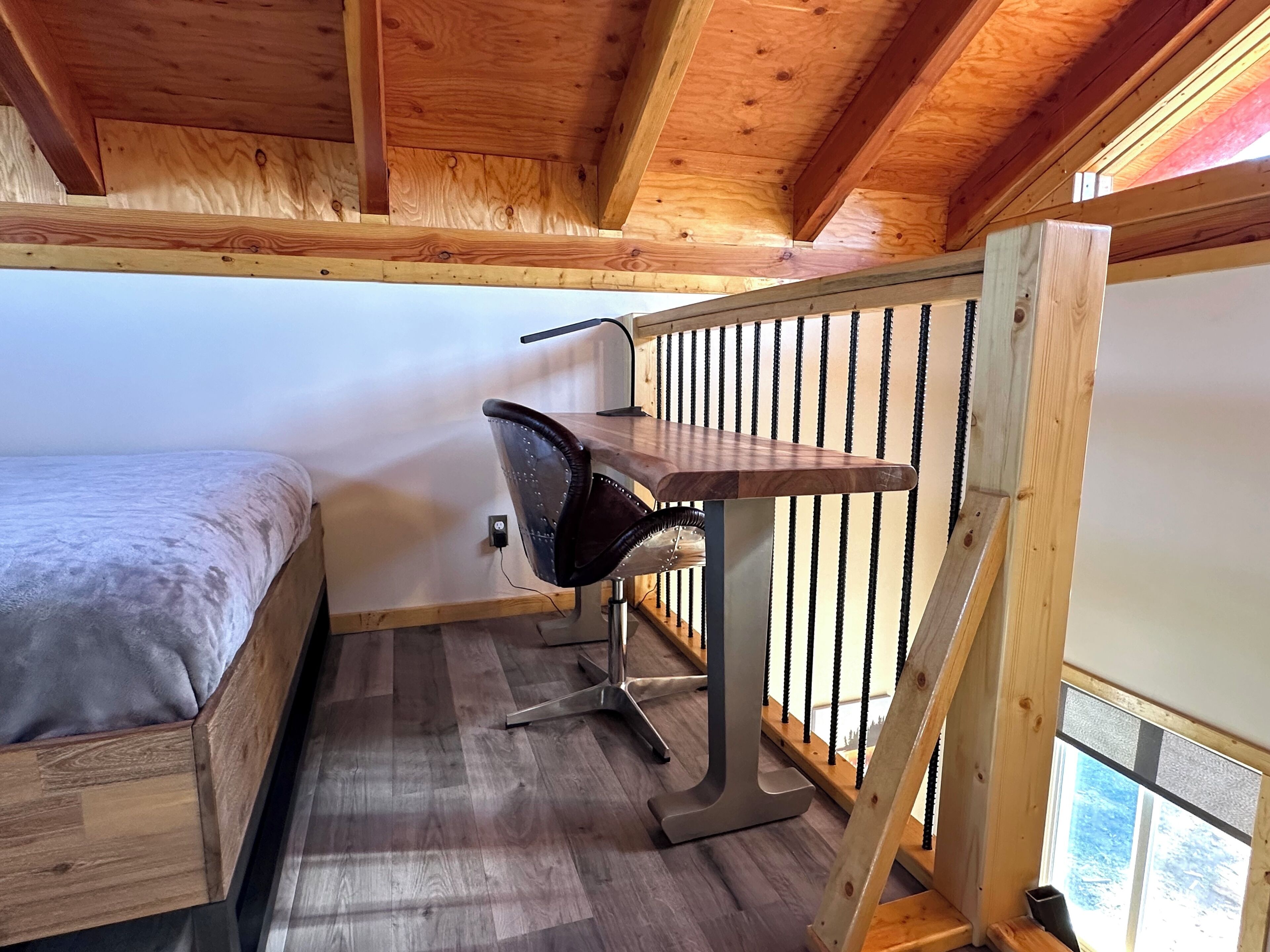 A small, cozy room with a wooden bunk bed, a desk with a chair, and a window.