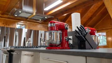 A kitchen with stainless steel appliances, a red mixer, and a knife block on the counter.