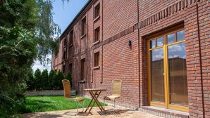 Un edificio in mattoni con un patio che include due poltrone in vimini e un tavolino.