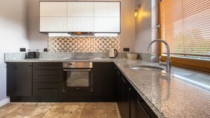 Una cucina moderna con forno integrato, lavello e finestra con persiane.