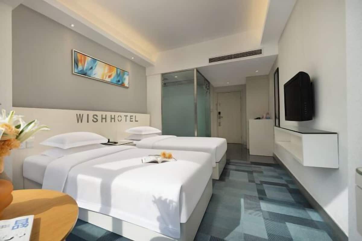 Une chambre d’hôtel avec deux lits, une télévision et un tableau au mur.